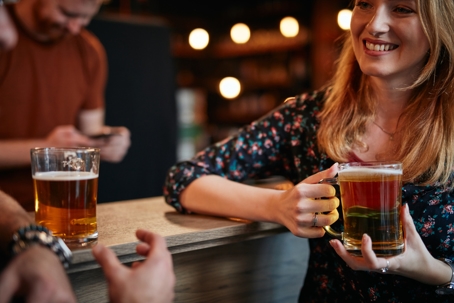 Blonde woman holding beer pint in a bar | Patituce & Associates