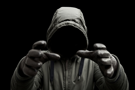 Mysterious man in hooded jacket with arms raised to strangle | Patituce & Associates