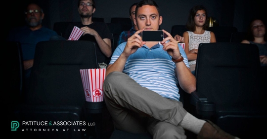 man filming in movie theater on phone