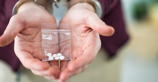 Man arrested in handcuffs for possession of illegal opiate pills.